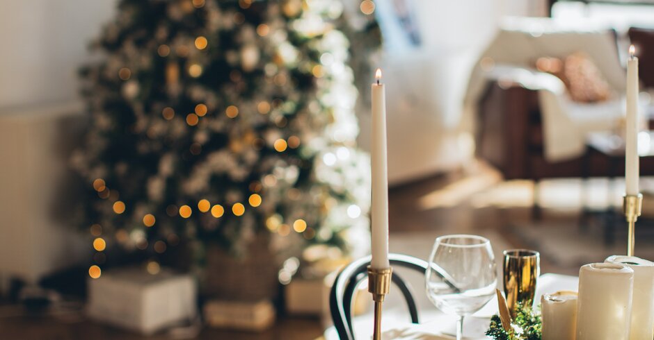 Weihnachtlich dekorierter Esstisch mit Weihnachtsbaum im Hintergrund