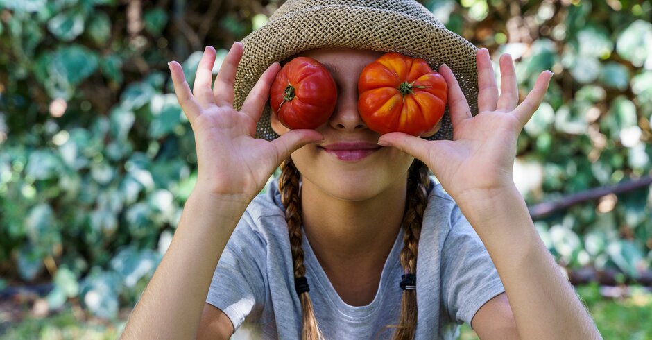 Junges Mädchen hält sich zwei Tomaten vor die Augen