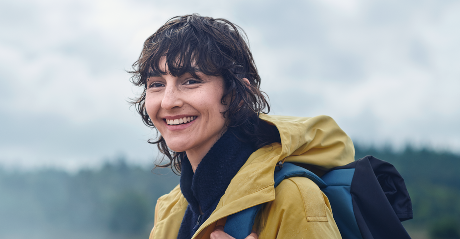 Lächelnde Frau mit Outdoor-Regenkleidung in der Natur