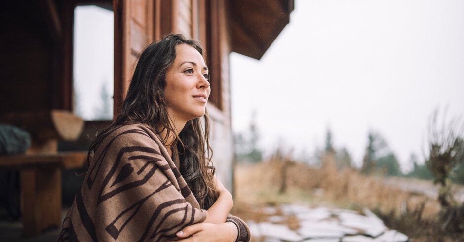Frau vor einem Haus genießt Ausblick in die Natur