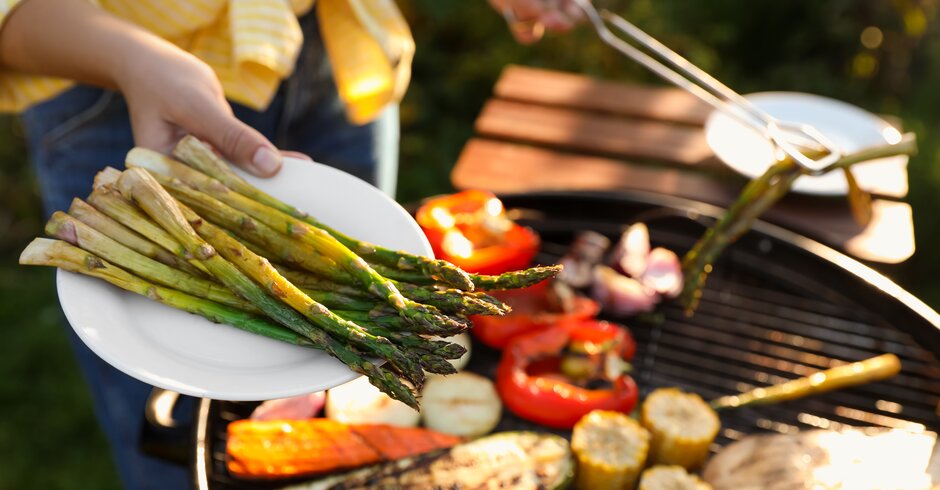 Frau grillt Gemüse auf einem Grillrost