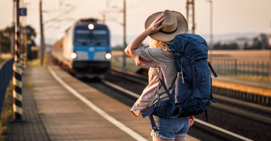 Junge Frau steht am Bahnsteig und wartet auf den Zug