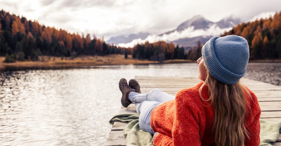 Frau liegt auf einem Steg am See