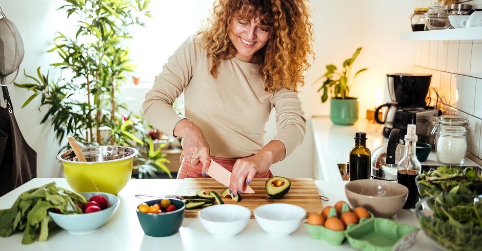 Frau schneidet Avocados in der Küche