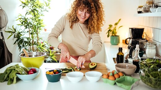 Frau schneidet Avocados in der Küche