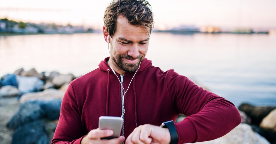 Mann joggt um einen See und misst seine Leistung mit einer Trackinguhr