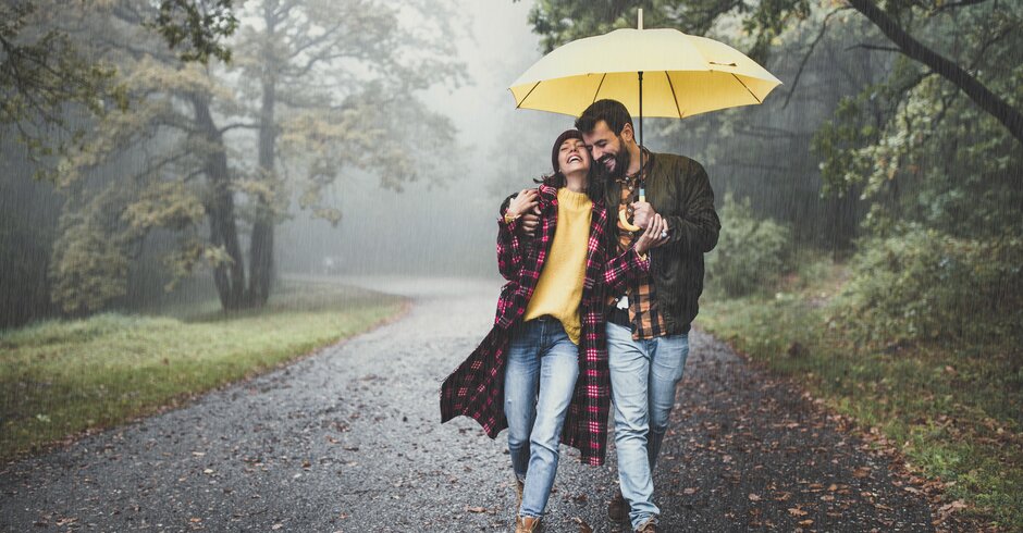 Pärchen geht im Regen mit einem Regenschirm spazieren